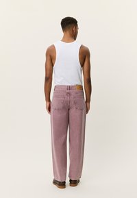 Ροζ ανοιχτόχρωμο τζιν με φαρδιά γραμμή, κατασκευασμένο από denim, με κλασικό σχέδιο πέντε τσεπών και καφέ δερμάτινο έλασμα στη μέση πίσω.