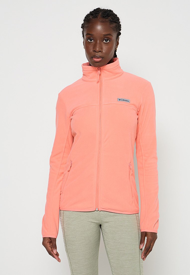 Lichte roze fleecjas met hoge kraag, ritssluiting aan de voorkant en zijzakken; heeft een klein merklogo op de borst.