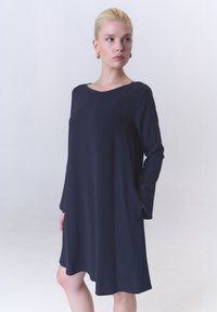 Dunkelblaues Langarmkleid mit rundem Ausschnitt, gefertigt aus einem glatten Stoff. Der Saum reicht bis zur Mitte des Oberschenkels und verfügt über Taschen in den Seitennähten.