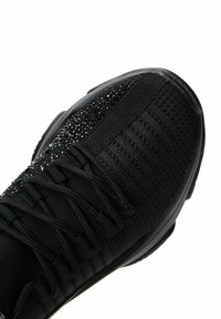 Black athletic shoe featuring a textured knit upper with sparkling accents, integrated lacing system, and a rounded toe design.