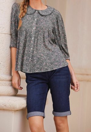 Groene blouse met bloemenprint, knoopsluiting aan de voorkant, geplooide textuur en ronde kraag, gecombineerd met donkere denim korte broeken met omslag.