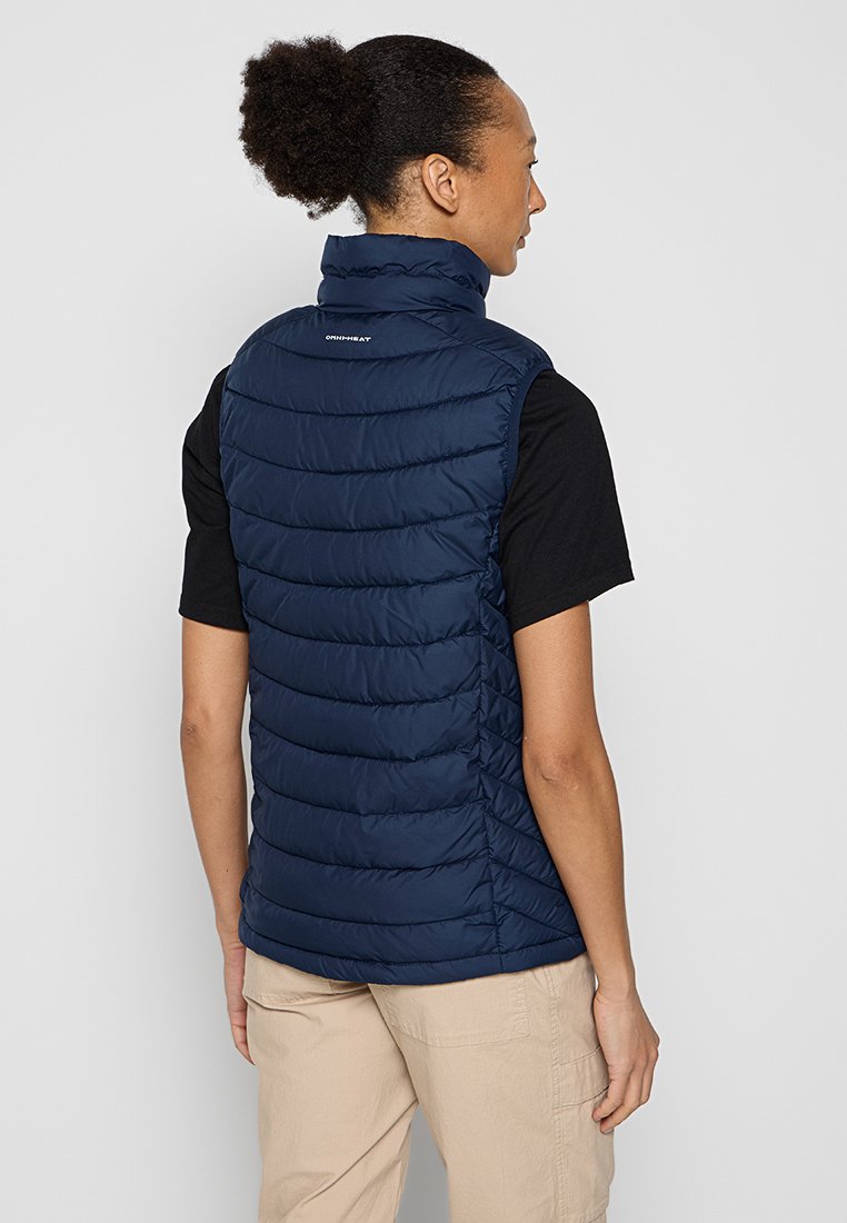 Gilet matelassé bleu marine avec un motif de quilting vertical, col montant et logo dans le dos. Fabriqué en matériau lisse et léger.