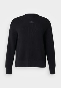 Pull en maille noire avec un encolure ronde et des manches longues. Présente un petit logo sur la poitrine ainsi que des bords côtelés aux poignets et à l'ourlet.