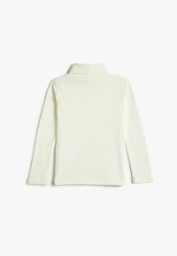 Top de cuello alto de manga larga en suave tela de canalé de color crema. Presenta un cuello alto y un diseño ajustado. Sin patrones ni adornos visibles.