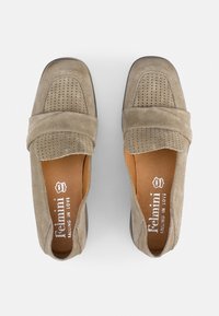 Mocasines de gamuza topo con un diseño frontal perforado, banda elástica y plantilla de cuero marrón. Suela plana con punta redonda.