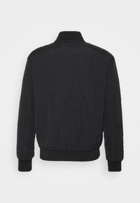 Černá prošívaná bomber bunda s žebrovanými manžetami a límcem. Na povrchu látky se nachází vyražený vzor loga. Jednoduchý, polstrovaný design.