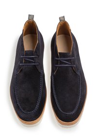 Scarpe in suede blu navy con punta arrotondata, design con lacci, accenti in pelle marrone a contrasto e suola in gomma. Include una piccola linguetta sul tallone.