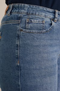 Vaqueros de mezclilla azul claro con un corte ajustado, que presentan un bolsillo trasero, costuras en contraste y una textura de tela suave.