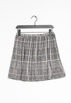 Czarna i biała spódnica w kratę z plisami, wykonana z tkaniny tkanej. Posiada talię z elastyczną gumką i jest zawieszona na czarnym plastikowym wieszaku.