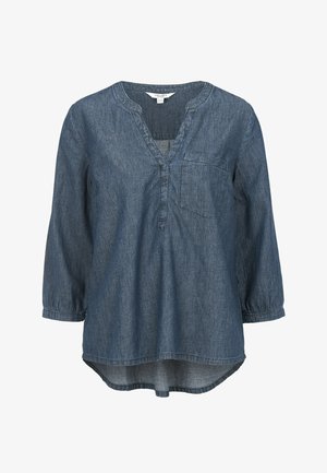 Denim-Tunika mit V-Ausschnitt, langen Ärmeln und einer aufgesetzten Tasche. Sie hat einen abgerundeten Saum und besteht aus einem weichen Stoff in einem mittleren Blauton.