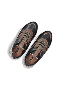 Zwarte en bruine sneakers met een gestructureerde bovenkant, contrasterende materialen, gaasdetails en lichtgekleurde zolen. De veters hebben metallic accenten.