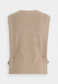 Gilet en maille côtelée beige avec un col rond et de larges emmanchures, présentant une finition texturée et des fentes sur les côtés.