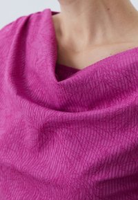 Fuchsia Textile mit einer strukturierten, gerippten Musterung. Der drapierte Stoff umschließt fest und zeigt das weiche, glatte Material und den subtilen Glanz.