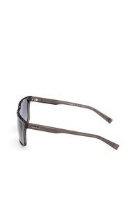 Gafas de sol de plástico marrón con lentes grises, que presentan un diseño elegante y un logo en la patilla. Las varillas tienen un agarre texturizado para mayor comodidad.