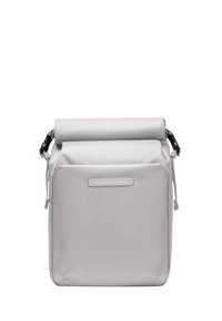 Sac à rouleau gris en tissu texturé. Il possède une poche avant avec une étiquette blanche horizontale et des accessoires de sangle réglables.