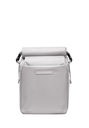 Sac à rouleau gris en tissu texturé. Il possède une poche avant avec une étiquette blanche horizontale et des accessoires de sangle réglables.