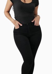 Czarny dopasowany t-shirt z krótkimi rękawami w zestawieniu z czarnymi, wysokim stanem spodniami. Gładka tkanina o eleganckim, przylegającym do sylwetki kroju.