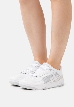 Białe sportowe trampki z cholewką ze skóry, sznurowane, z perforowanym noskiem oraz szarymi akcentami po bokach i na pięcie dla dodatkowego detalu.