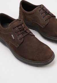 Chaussures à lacets en suède marron avec un bout arrondi, des coutures contrastantes et une semelle en caoutchouc noire durable. Présentent un petit accent métallique.