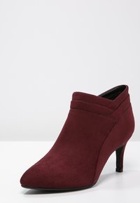 Burgundowe botki za kostkę z sztucznego zamszu, z wydłużonym noskiem, dekoracyjnym przeszyciem i cienkim obcasem typu stiletto. Gładkie, miękkie wykończenie wewnętrzne.