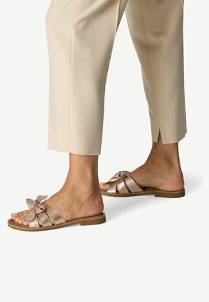 Sandales plates en or rose avec une finition texturée, présentant un grand nœud sur l'orteil et un design simple à bout ouvert.