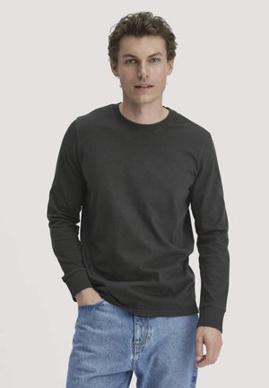 Zwart langarmshirt van katoen, met een ronde hals en ribgebreide manchetten. Gezegd met lichtblauwe spijkerbroek.