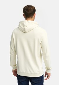 Lyscremet hætten - sweatshirt med tekstureret ribbet design, justerbar snøre og ribbede manchetter og kant. Bagudsigten.