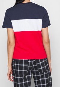 Katoenen T-shirt met een color block ontwerp: marineblauwe, witte en rode secties. Korte mouwen, ronde hals, gecombineerd met zwart-witte geruite broek.