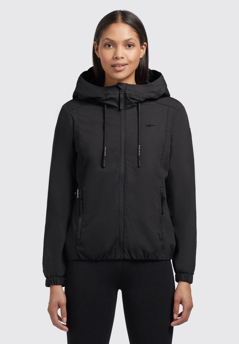 Veste à capuche noire avec un zip sur le devant, des cordons de serrage, des manches élastiques et deux poches zippées sur les côtés. Tissu lisse et léger avec une finition mate.