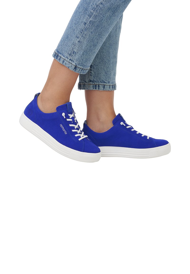 Blaue Wildledersneaker mit weißen Schnürsenkeln und Gummisohlen. Ausgestattet mit einer runden Zehenpartie und einem seitlichen Logodetail. Tragen kombiniert mit hochgekrempelten hellen Jeans.