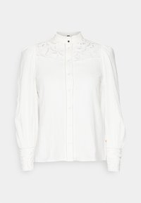 Blouse blanche à manches longues avec empiècement en dentelle et poignets, col haut, fermeture à boutons sur le devant et épaules bouffantes.