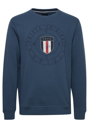 Kraljevo modra jopica iz blenda bombaža. Ima okroglo ovratnik, rebraste manšete in osrednjo grafiko logotipa s ščitom ter letnico "1924".