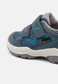 Blauer Wanderschuh mit einem Mesh-Obermaterial und Wildlederakzenten. Verfügt über einen Klettverschluss, kontrastierende türkise Linien und eine strukturierte Gummisohle.