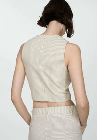 Cropped sleeveless top in light beige with vertical stripes, featuring a round neckline and fitted design, paired with matching high-waisted pants.