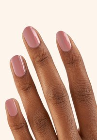 Nagellak op vijf vingers met een gladde, glanzende afwerking; de kleur is zachtroze. De huid heeft een medium bruine toon met zichtbare textuur.