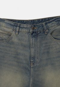 Vaqueros de mezclilla azul con un acabado desgastado, cinco bolsillos, cierre de botón metálico y costuras en contraste a lo largo de las costuras.