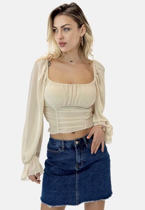 Ecru, geraffter Crop-Top mit langen, luftigen Ärmeln; kombiniert mit einem blauen Denim-Minirock mit rohem Saum und vorderen Knöpfen.