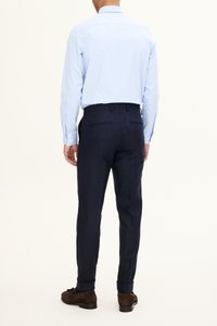Ljusblå skjorta med knappar och mörkblå byxor, med skräddarsydd passform, slät textur och kontrasterande manschettdetaljer. Bruna skor syns.