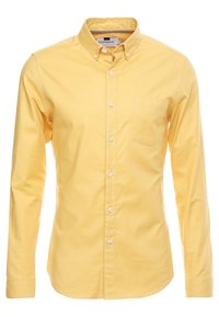 Męska koszula z długim rękawem w kolorze żółtym, z guzikami i kołnierzykiem zapinanym na guziki oraz kieszonką na piersi, wyeksponowana na białym tle.