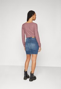 Purple ribbed long-sleeve top paired with a blue denim mini skirt and black lace-up boots with yellow accents, viewed from the back.
