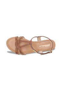 Sandalo in pelle marrone con suola piatta, dotato di più sottili cinturini, un dettaglio annodato sulla punta e un plantare beige chiaro contrassegnato dal marchio.