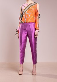 Blusa colorata con spalle scoperte e motivo a catena abbinata a pantaloni viola brillanti. Entrambi realizzati in tessuto leggero e morbido.