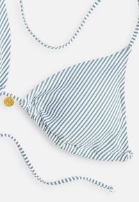 Haut de bikini triangle rayé bleu et blanc avec fines bretelles réglables et un petit pendentif rond en or attaché sur un côté.
