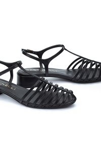 Sandalias negras de tiras con un diseño geométrico, que cuentan con un tacón bloque de altura media y un acabado de cuero suave. Realzadas con delicadas correas.