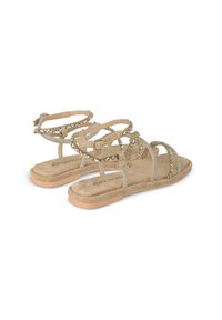 Sandali piatti beige con molteplici cinturini sottili, decorati con perline e strass; soletta morbida e testurizzata, design minimalista.