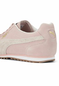Sneaker din suede roz cu o dungă texturată bej, talpă albă și logo auriu pe călcâie. Are o siluetă rotundă și guler căptușit.