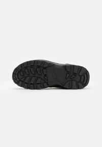 Svart sportsko såle med fremtredende mønstre, buede kanter og en sentral Nike-logo. Laget av gummi og syntetiske materialer.