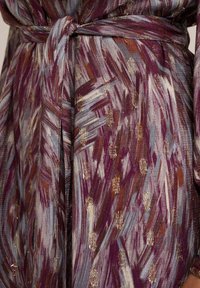 Tessuto a fantasia viola e grigio con accenti dorati, caratterizzato da una cintura annodata e un design a pennellate. Texture morbida, caduta elegante.