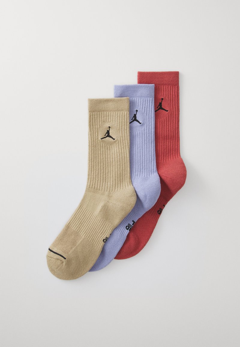 Trois paires de chaussettes côtelées en beige, lavande et rouge, chacune affichant un logo Jumpman noir. Mélange de coton avec des orteils renforcés.