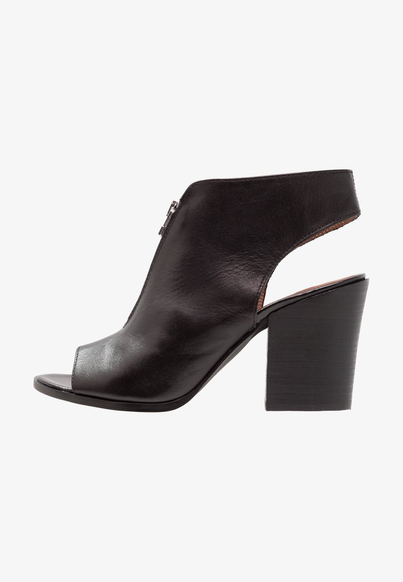 Bottine femme en cuir noir à bout ouvert, talon bloc et fermeture éclair latérale, avec une découpe à l'arrière.